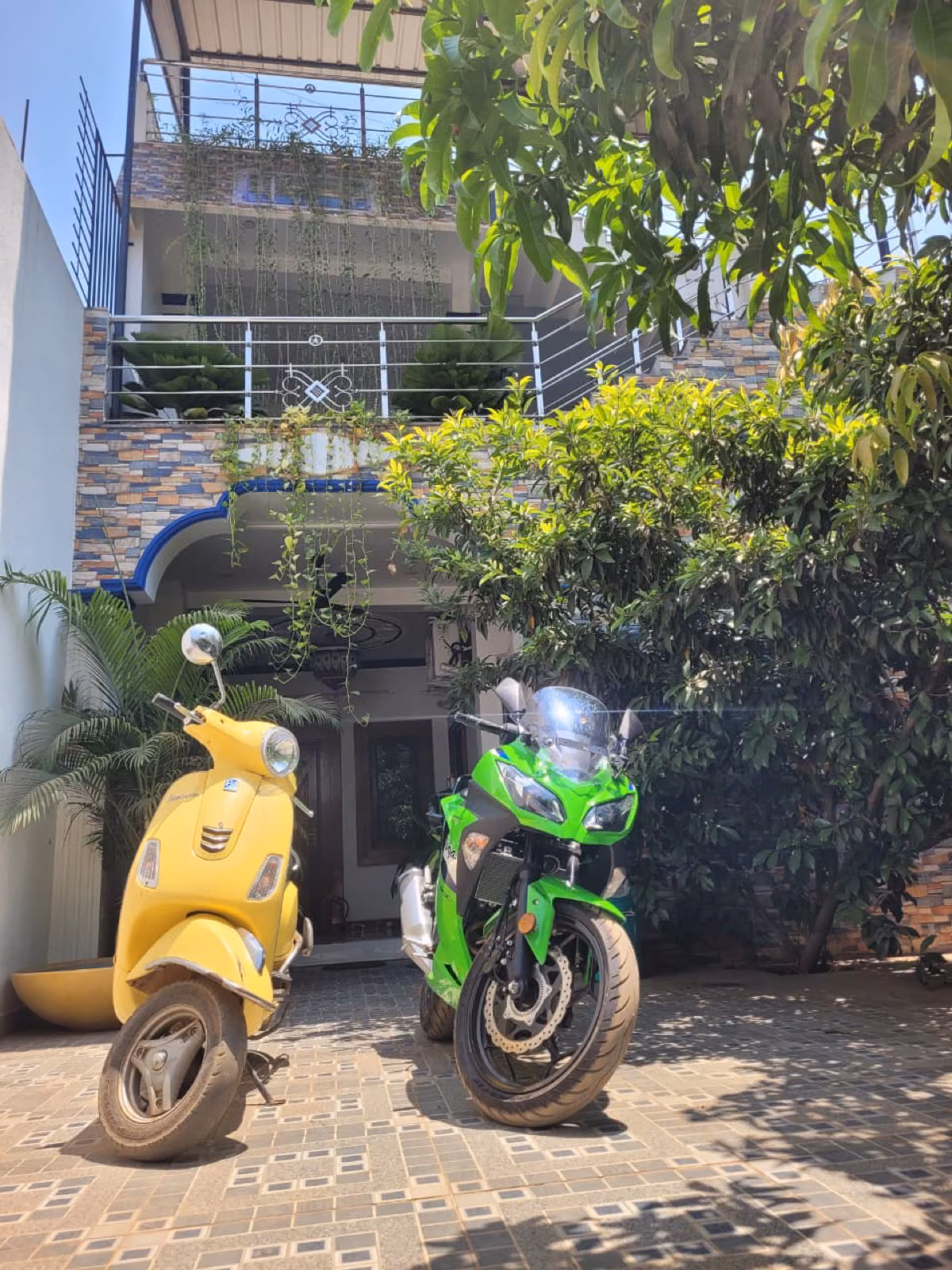 Yellow Vespa and Kawasaki Ninja parked at Nivaa Stays facade