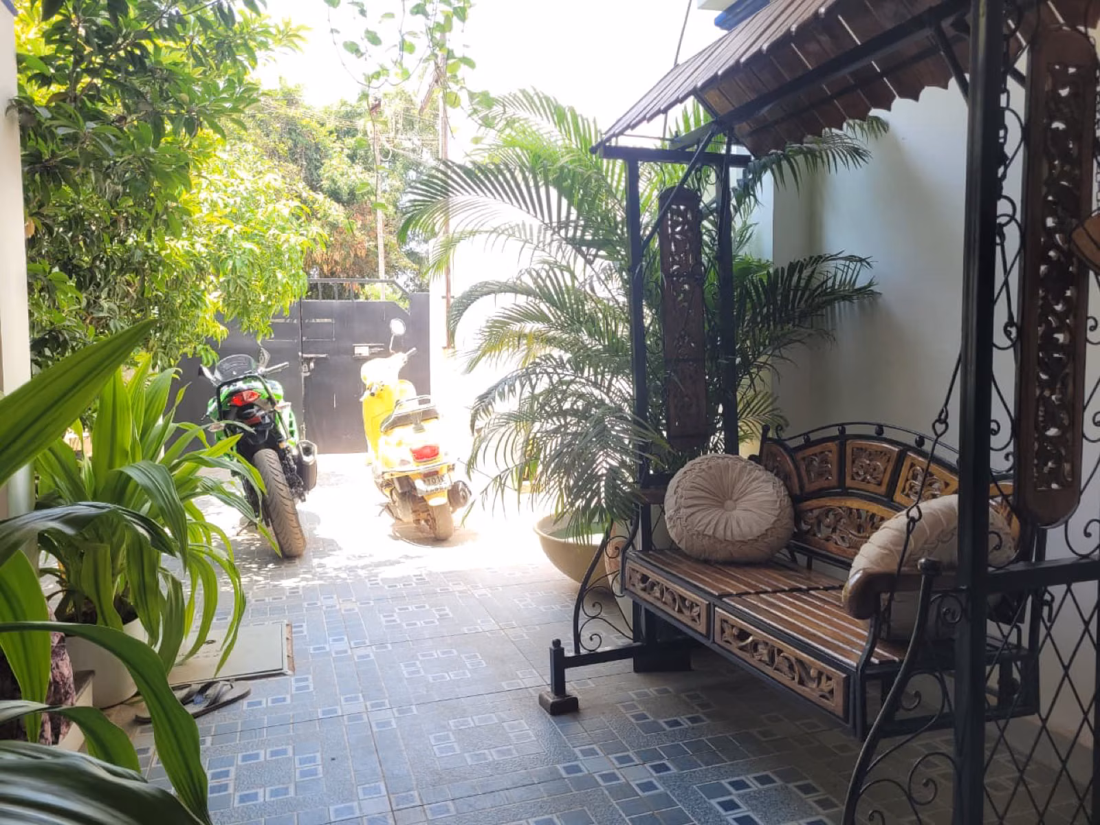 Wooden swing porch with yellow Vespa and Kawasaki Ninja at Nivaa Stays entrance