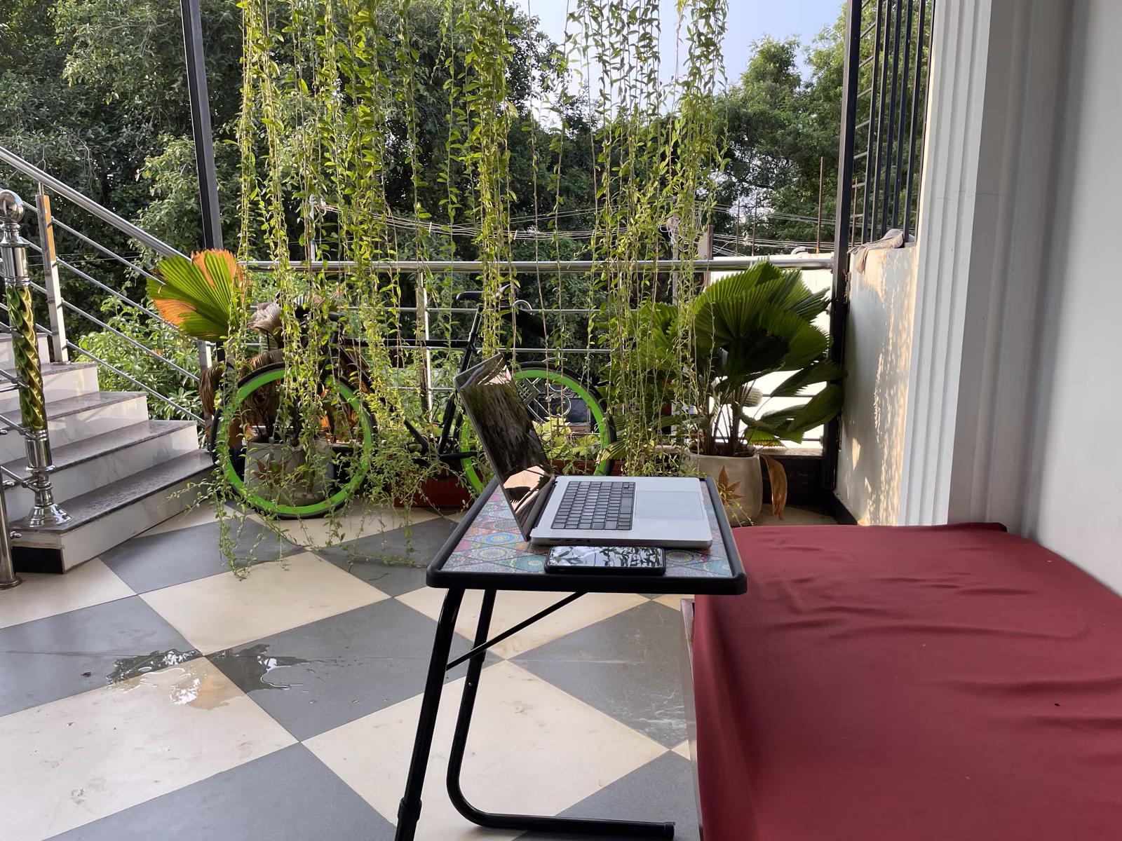 MacBook on an adjustable laptop stand on the Nivaa Stays balcony — set up for remote work in Pondicherry
